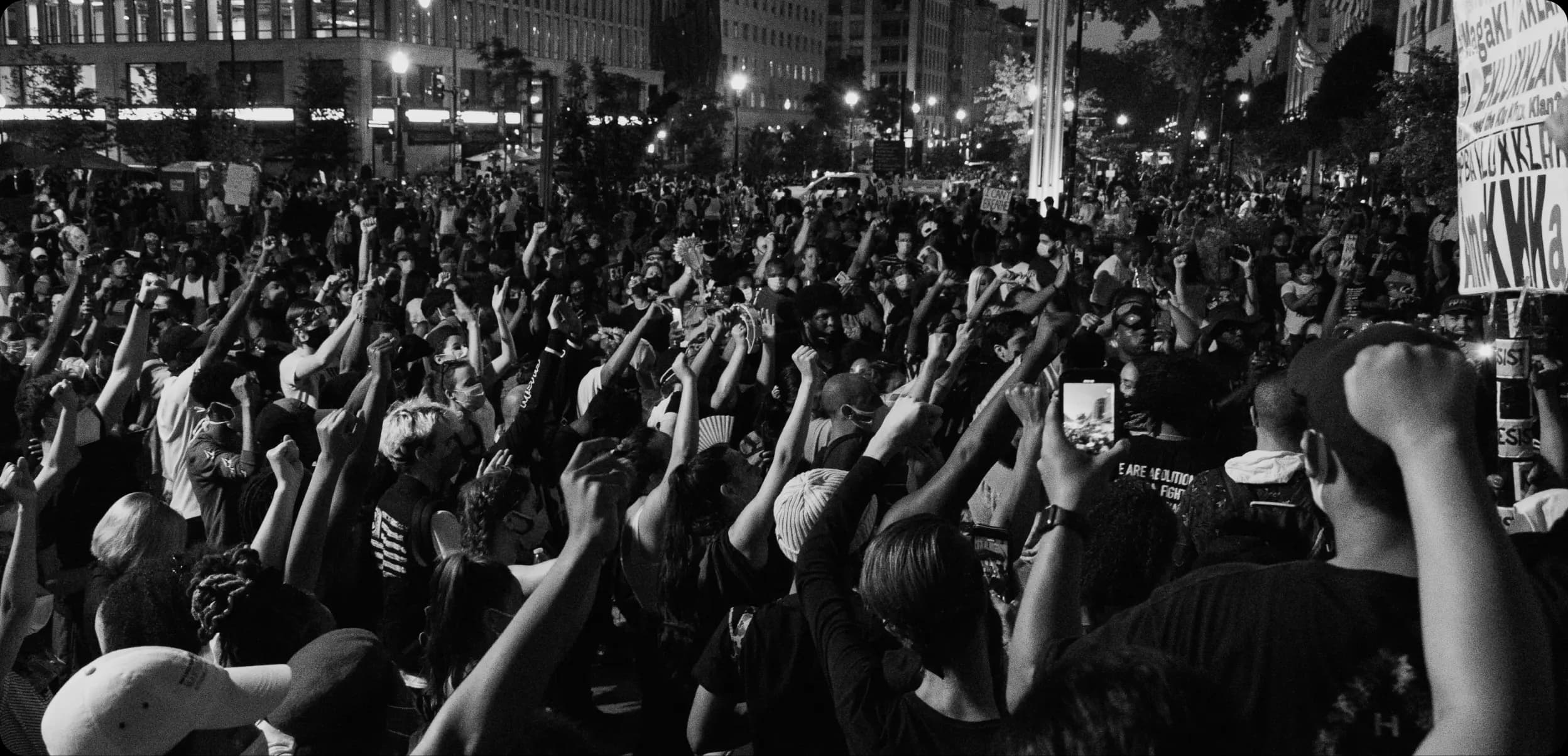 grayscale image of people raising their hands up